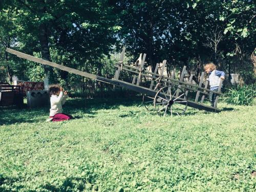 two children playing with a woodenmill in the grass at Lazuri Keria Family Guesthouse in Khoni