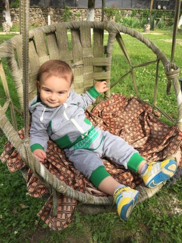 a young boy is sitting in a swing at Lazuri Keria Family Guesthouse in Khoni