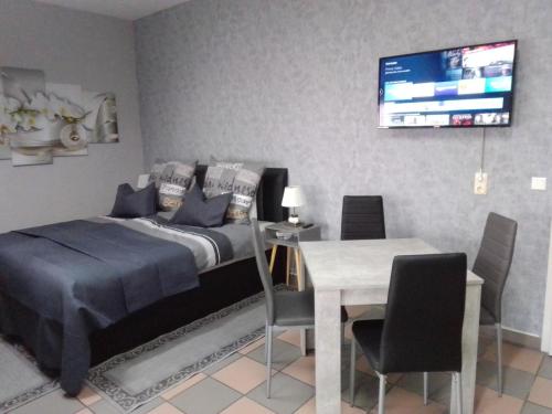 1 dormitorio con cama, mesa y TV en Orchideen Zimmer, en Wetzlar