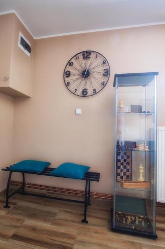 a clock on a wall with a bench and a glass case at Vila Chess in Belgrade