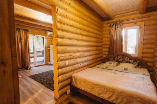 a bedroom with a bed in a log cabin at Nika2 Hotel in Zatoka