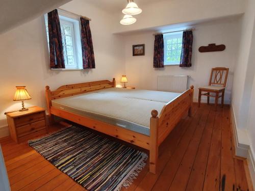 1 dormitorio con 1 cama grande de madera y 2 ventanas en Wächterhaus auf der Sauerburg, en Sauerthal
