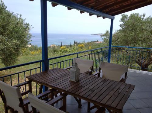 a wooden table and chairs on a balcony with the ocean at Aggeliki House 3 in Kómboi