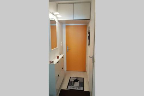 a hallway with an orange door and a bathroom at Ferienwohnung Berolina 116 in Dahme