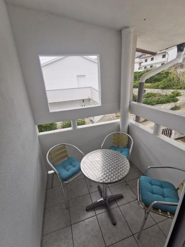 a balcony with two chairs and a table and a window at Laura's dream Appartments in Pag