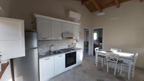 a kitchen with white cabinets and a table with chairs at Dimora Igea b&b in Montano Antilia