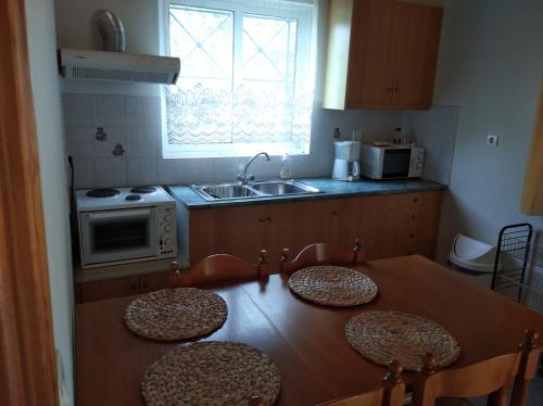 cocina con mesa de madera con sillas y fregadero en Aggeliki House 3, en Kómboi
