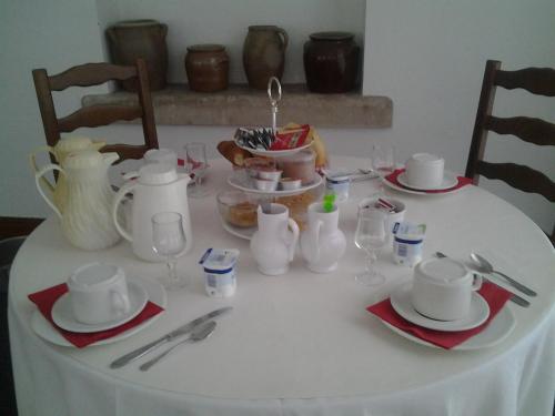 a white table with plates and cups and utensils at La Renaudière in Chenonceaux