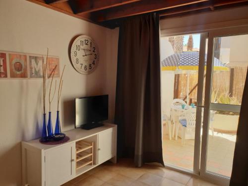 a room with a clock on the wall and a television at oasis RELAX Corralejo in Parque Holandes