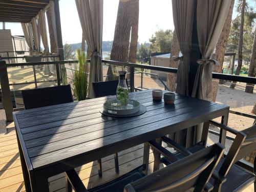 a wooden table with chairs and a bottle on a balcony at HARMONIA mobile home in Rovinj