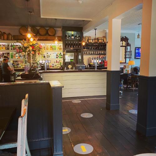 a bar with a woman sitting at a counter at Castle Hotel in Eynsford