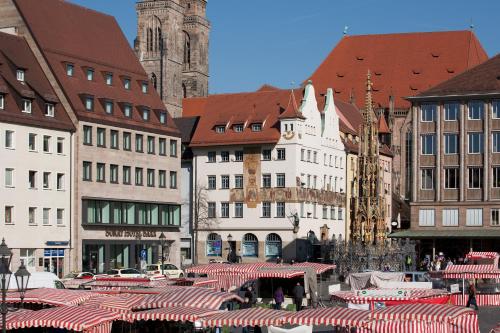 a group of buildings with red and white tables at Sorat Hotel Saxx Nürnberg in Nürnberg