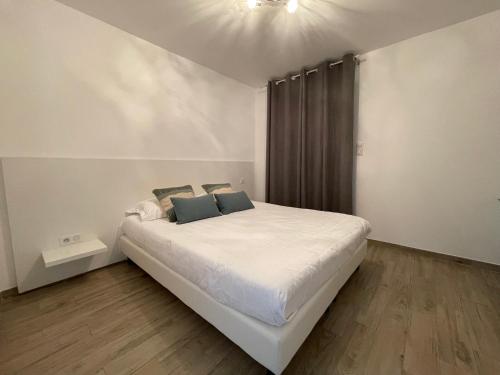 Schlafzimmer mit einem Bett mit weißer Bettwäsche und blauen Kissen in der Unterkunft Residence Des Îles in LʼÎle-Rousse
