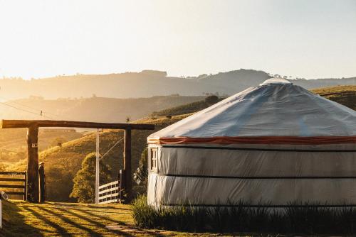 a yurt in a field with a hill in the background at Yurt, romântico e luxuoso, natureza e cachoeiras in Jacutinga