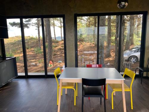 a table and chairs in a room with windows at Refúgio do Canyon in Balsa Nova