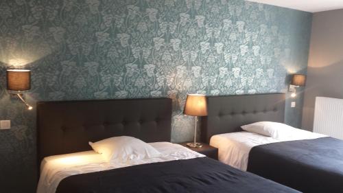 a bedroom with two beds and a wall with wallpaper at Hotel La Fayette in Rochefort
