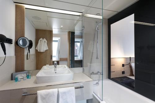 a bathroom with a sink and a shower and a mirror at Sorat Hotel Saxx Nürnberg in Nürnberg