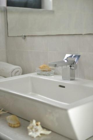 a white bathroom with a sink and a mirror at Chateau de Georges in Gythio