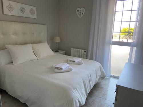 Un dormitorio con una cama blanca con toallas. en Karin Palma Fiesta-Vallpineda-Sitges, en Sant Pere de Ribes