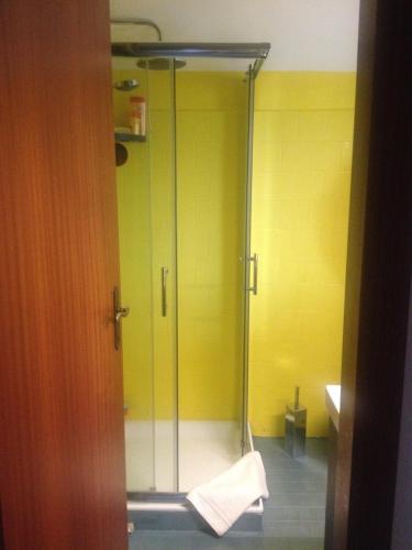 a glass shower in a bathroom with a yellow wall at Residenza Il Porto in Padenghe sul Garda