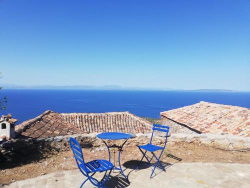 two blue chairs and a table on a patio overlooking the ocean at The traditional hause with the best view in Leonidion