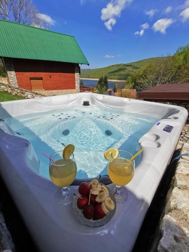 a hot tub with two glasses of juice and fruit in it at Sindy Wooden Apartments in Mavrovo