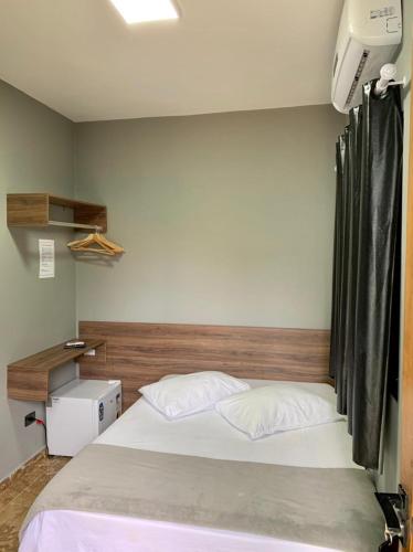 a bedroom with a white bed with a wooden headboard at Santa Cecília Pousada in Guarujá