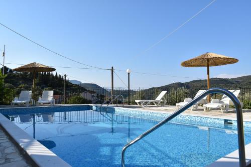 a swimming pool with an umbrella and chairs at Panorama in Vathi, Ithaka