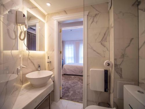 a white bathroom with a sink and a mirror at The Moon Boutique Hotel in Sofia
