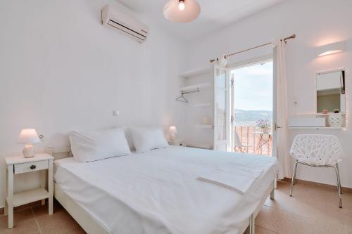 a white bedroom with a white bed and a window at Meltemi Antiparos in Antiparos