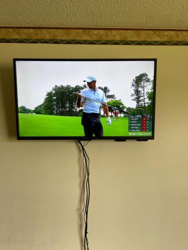 a television on a wall with a picture of a golfer at Hunter Lodge in Ripley