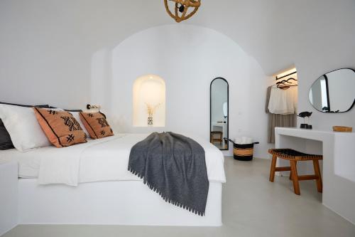 a white bedroom with a bed and a mirror at Blue Art Caves in Oia