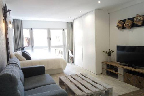 a living room with a couch and a bed and a television at Loft Bazán - Centro Alicante in Alicante