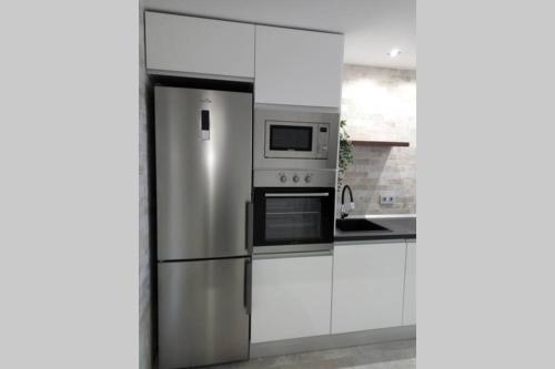 a kitchen with white cabinets and a stainless steel refrigerator at Loft Bazán - Centro Alicante in Alicante