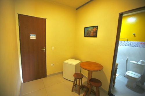 a bathroom with a toilet and a table and stools at Colonial Hotel in Ilhabela