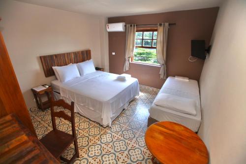 a small bedroom with a bed and a window at Colonial Hotel in Ilhabela