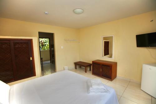 a bedroom with a white bed and a television at Colonial Hotel in Ilhabela
