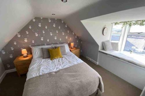 a attic bedroom with a bed and a window at Chemist's House in Cullen