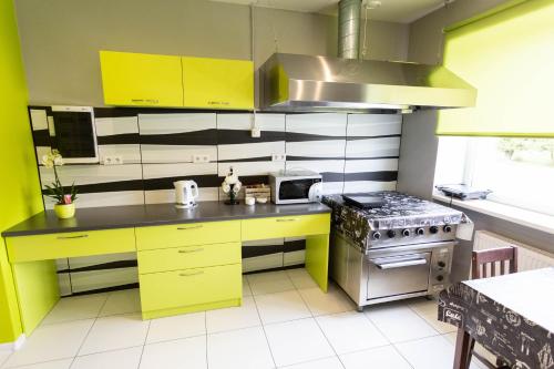 a kitchen with yellow cabinets and a stove at Lauvas Līcis in Rūjiena