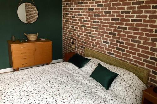 een slaapkamer met een bed met een bakstenen muur bij Gîte« Le Pressoir » chez viticulteur en biodynamie in Avenay-Val-dʼOr