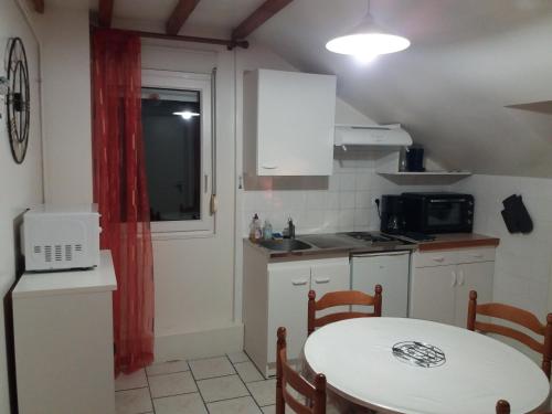 a small kitchen with a table and a microwave at Appartement 3 personnes tout équipé VOSGES. in Rochesson