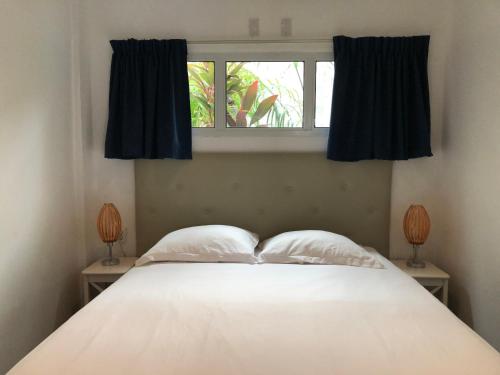 a white bed with two pillows and a window at Holland Lodge Paramaribo in Paramaribo