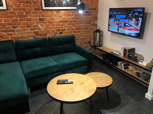 a living room with a green couch and a table at Stylowy apartament tuż przy Rynku in Ostrów Wielkopolski