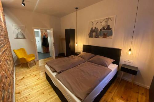 a bedroom with a large bed and a yellow chair at Stylowy apartament tuż przy Rynku in Ostrów Wielkopolski