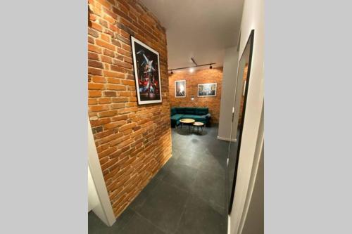 a hallway with a brick wall and a green couch at Stylowy apartament tuż przy Rynku in Ostrów Wielkopolski