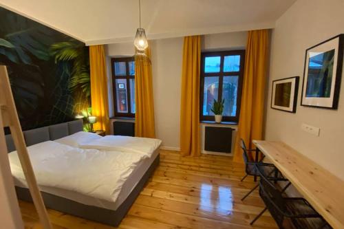 um quarto com uma cama, uma mesa e janelas em Stylowy apartament tuż przy Rynku em Ostrów Wielkopolski