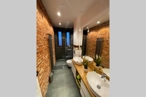 La salle de bains est pourvue de 2 lavabos et d'un mur en briques. dans l'établissement Stylowy apartament tuż przy Rynku, à Ostrów Wielkopolski
