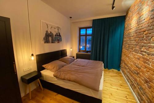 a bedroom with a bed and a brick wall at Stylowy apartament tuż przy Rynku in Ostrów Wielkopolski