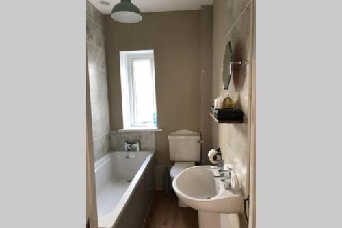 La salle de bains est pourvue d'une baignoire, d'un lavabo et de toilettes. dans l'établissement Seacot Cottage in the heart of the Highlands, à South Kessock