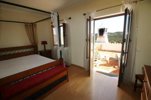 a bedroom with a bed and a sliding glass door at Paz e Natureza in São Brás de Alportel